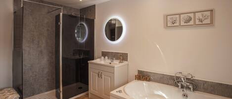 A modern bathroom with a walk-in shower, a freestanding bathtub, and a vanity with a mirror.