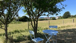 A metal table and two chairs set up outdoors, surrounded by grass and trees. - Kenfig Farm (Pyle)