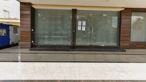 A building facade with large glass doors, a metal structure to the left, and a wooden panel design. - Red Cherry (Gurugram)