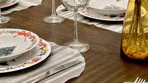 A dining table set with plates, glasses, and cutlery, a vase with flowers, and a Christmas tree in the background. - Immersed in the scenery of Canmore (Canmore)