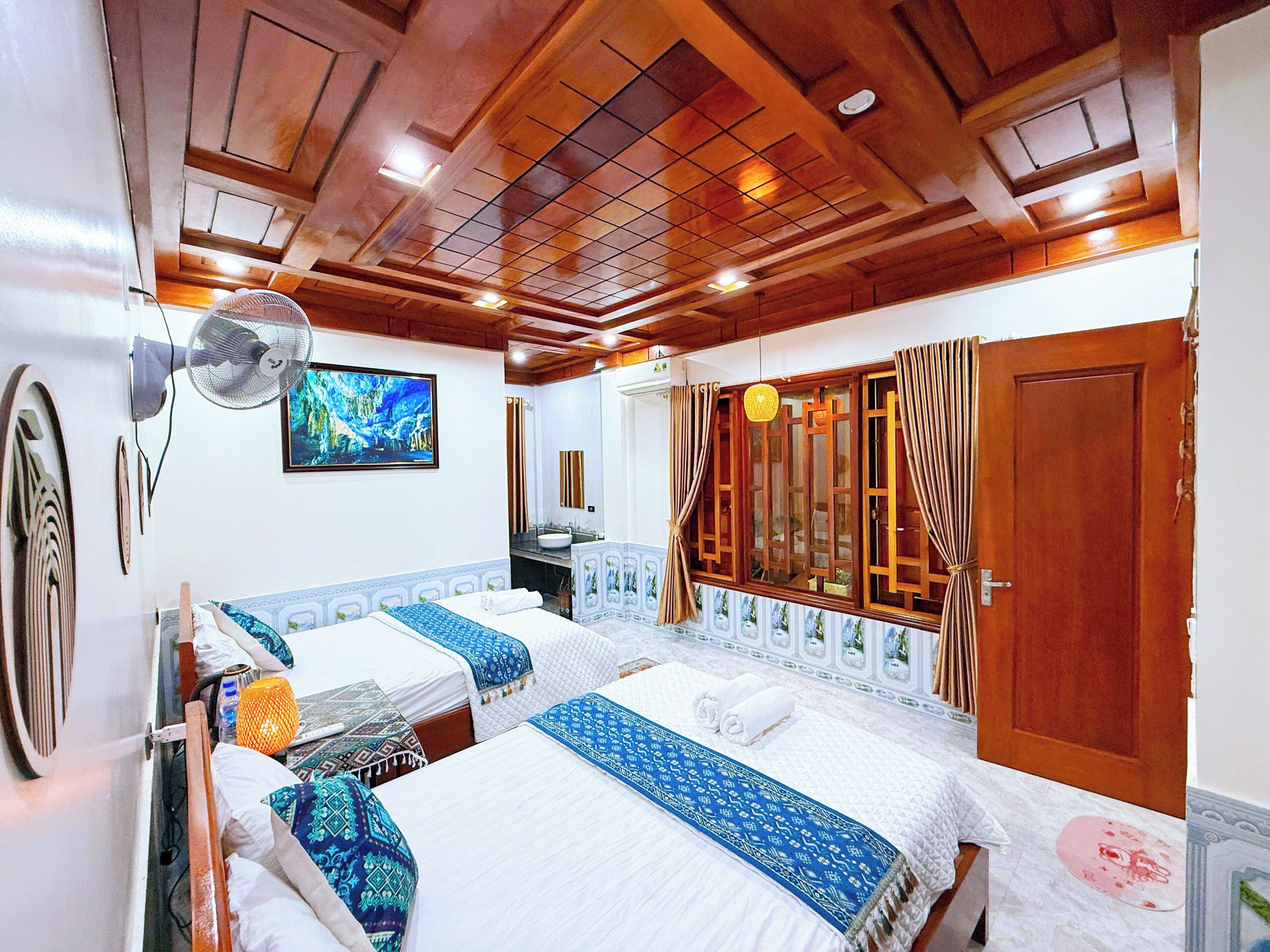 A hotel room with two beds, a large mirror, a ceiling fan, and a bathroom visible through an open door.