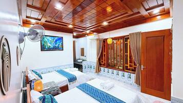 A hotel room with two beds, a large mirror, a ceiling fan, and a bathroom visible through an open door.