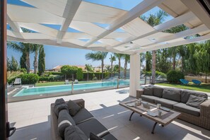 Ein überdachter Außenbereich mit Pool, einer Couch und einem Tisch.