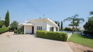 Une maison moderne dotée d’une antenne parabolique, d’une piscine et d’un jardin bien entretenu.
