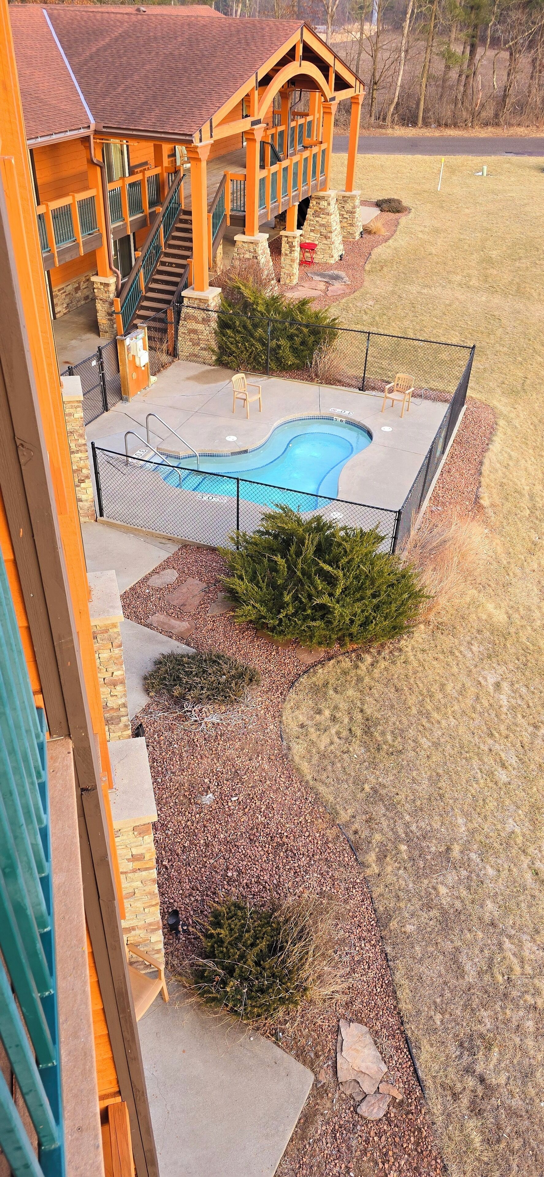 Una casa in legno con piscina, scalini in pietra e patio recintato.