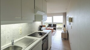 A modern kitchen with a built-in stove, a sink, and a microwave. There is a small dining area with a table and chairs.