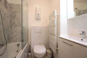 Ein modernes Badezimmer mit einer Duschkabine, einer Toilette, einem integrierten Waschbecken und einem Wandheizkörper.