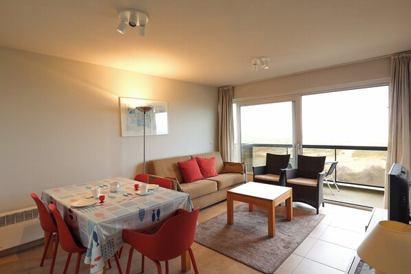 Ein Wohnzimmer mit Sofa, Esstisch, Stühlen und einem Balkon mit Blick.