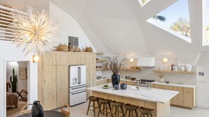 Une cuisine moderne dotée d’un îlot central, de meubles en bois et d’une grande verrière.
