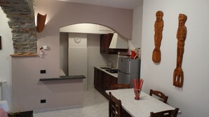 A modern kitchen with a stone accent wall, a built-in oven, and a dining area with a white table and chairs.