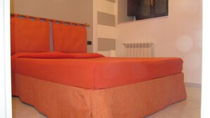 A room with a bed, a radiator, and a wall-mounted cabinet.