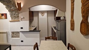 A compact kitchen with a stone accent wall, a heart-shaped decoration, and a modern refrigerator.