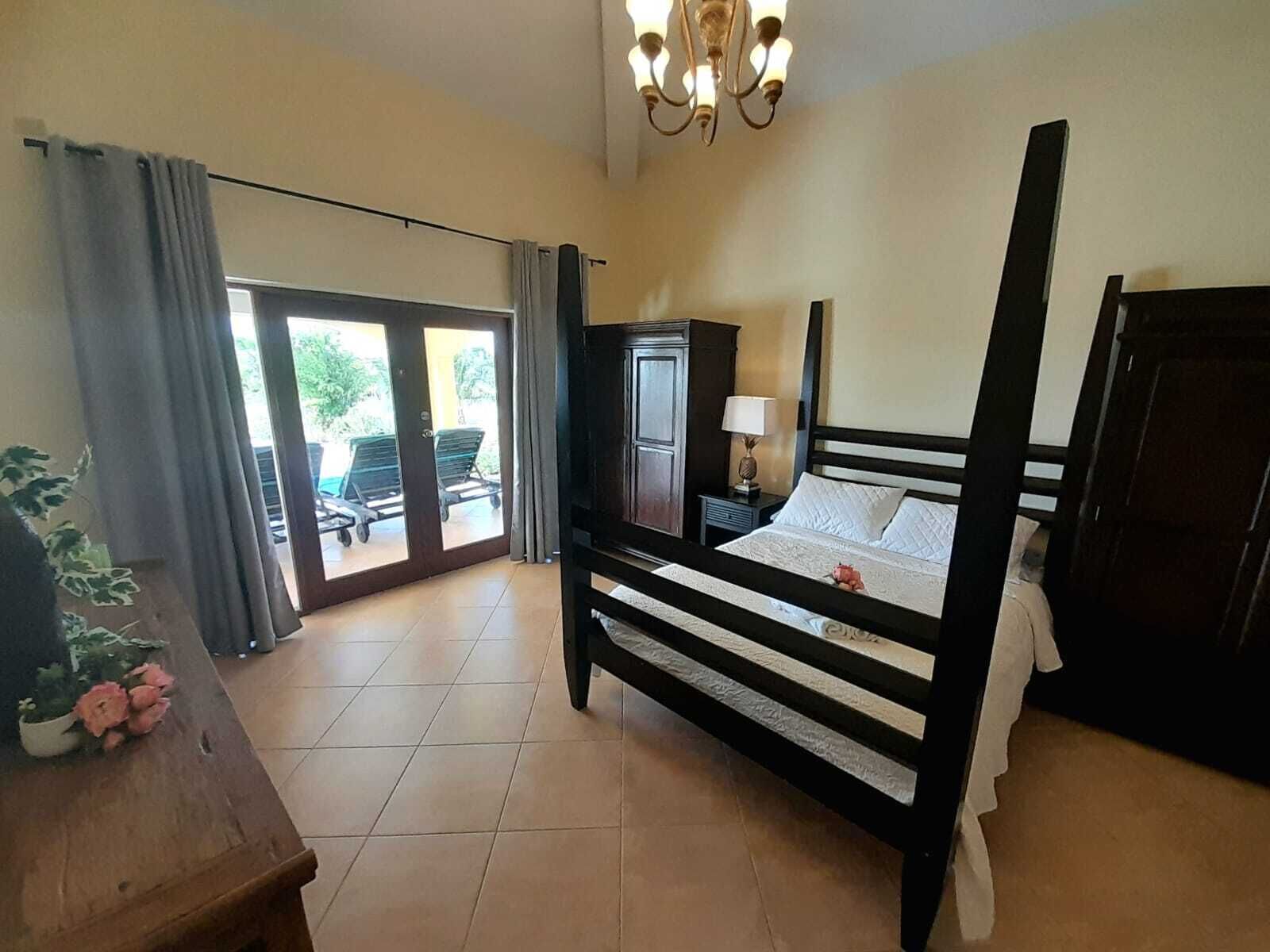 Una camera da letto con un letto a baldacchino, un comodino, una lampada e vista sull'esterno tramite una porta scorrevole.