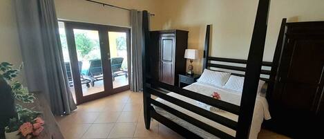 Una camera da letto con un letto a baldacchino, un comodino, una lampada e vista sull'esterno tramite una porta scorrevole.