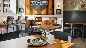 A café interior with wooden tables and chairs, a coffee machine, and a menu board. - Ironworks (New Orleans)