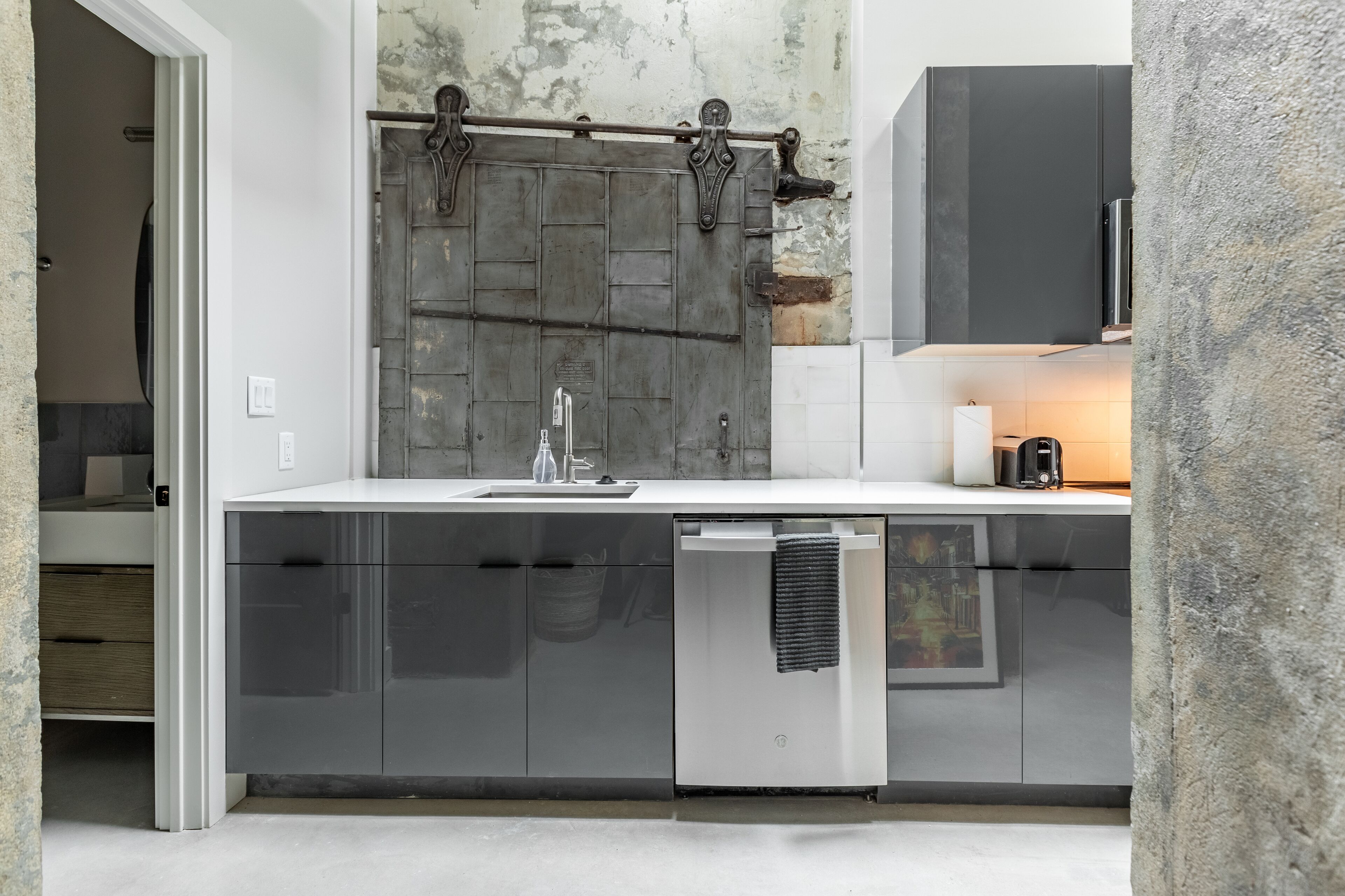 A modern kitchen with a large wooden door, a dishwasher, and a built-in oven.
