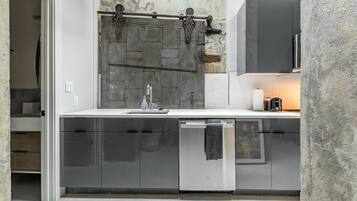 A modern kitchen with a large wooden door, a dishwasher, and a built-in oven.