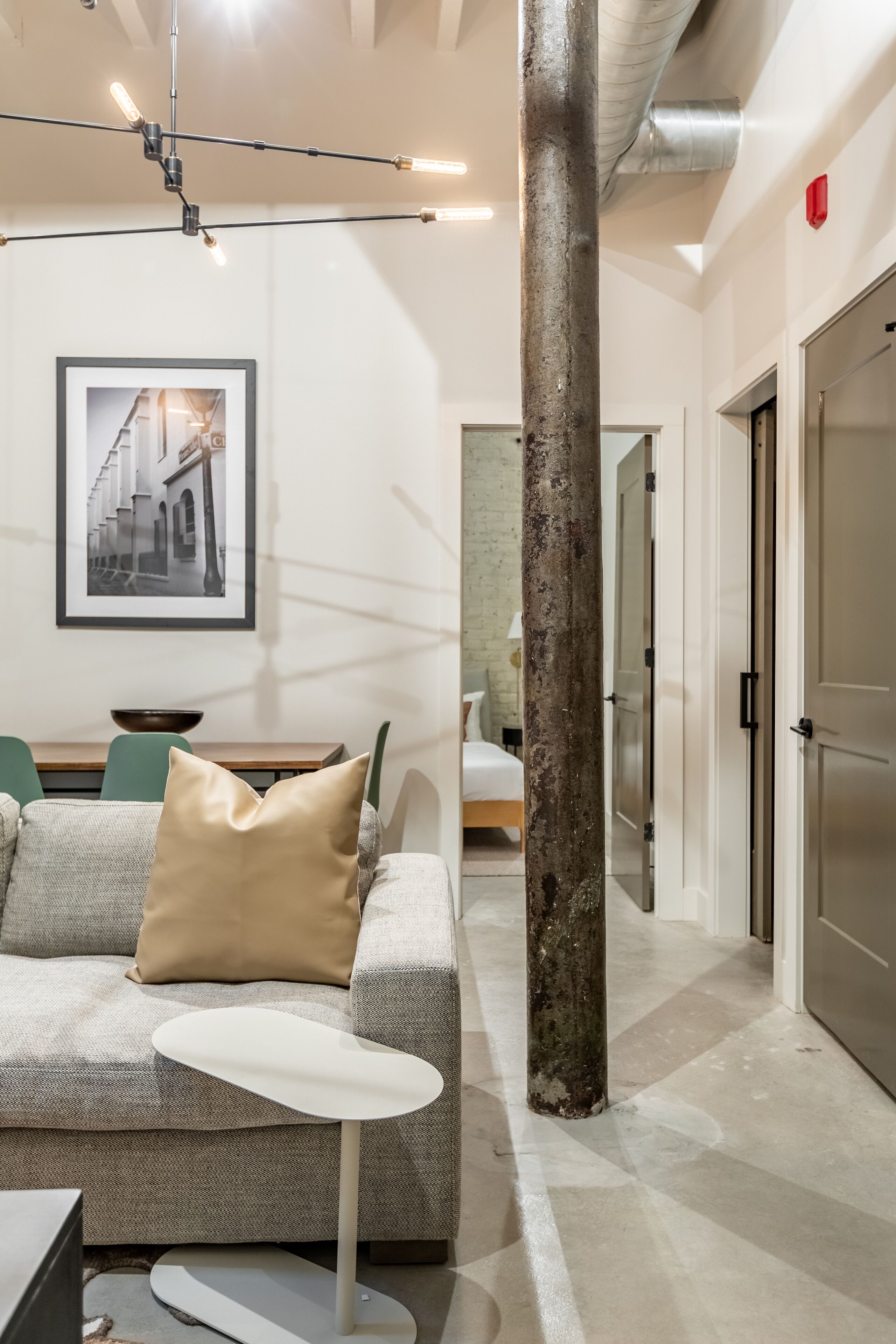 Um interior moderno com um sofá, uma mesa pequena, um pilar grande e um quadro na parede.