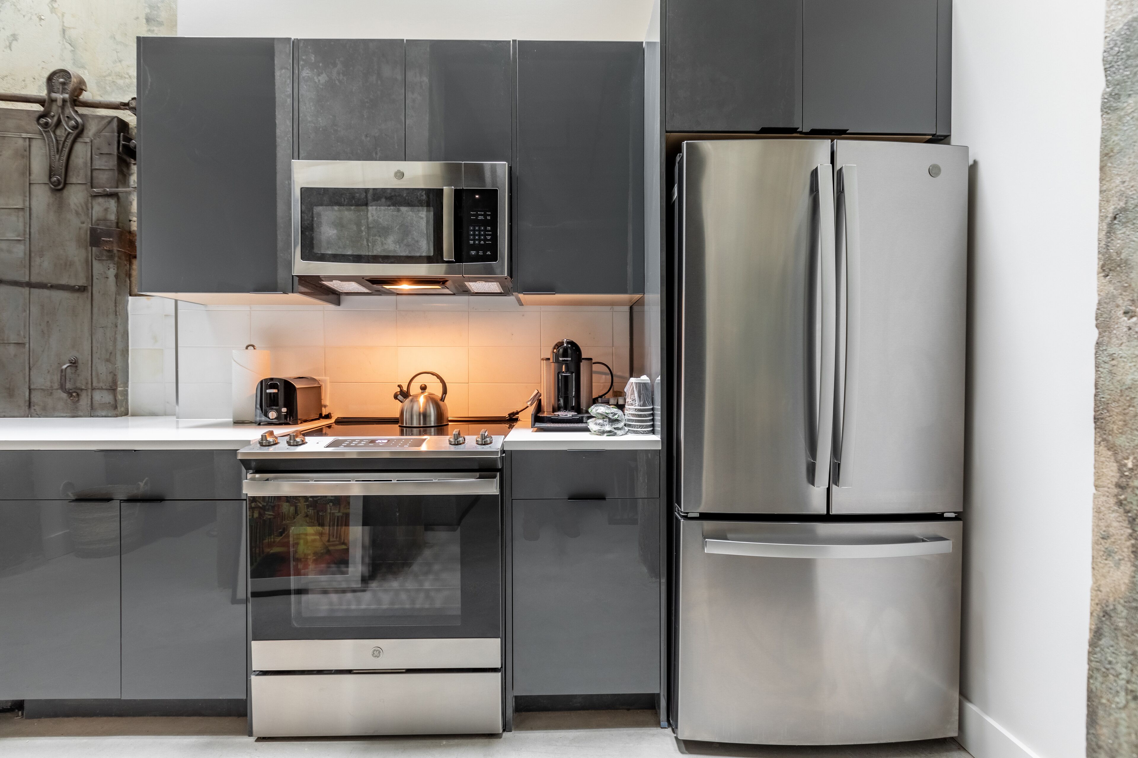 Una cocina moderna con electrodomésticos de acero inoxidable, incluyendo un microondas, horno y refrigerador.