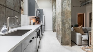 A modern kitchen with a large island, stainless steel appliances, and a concrete pillar. - Ironworks (New Orleans)