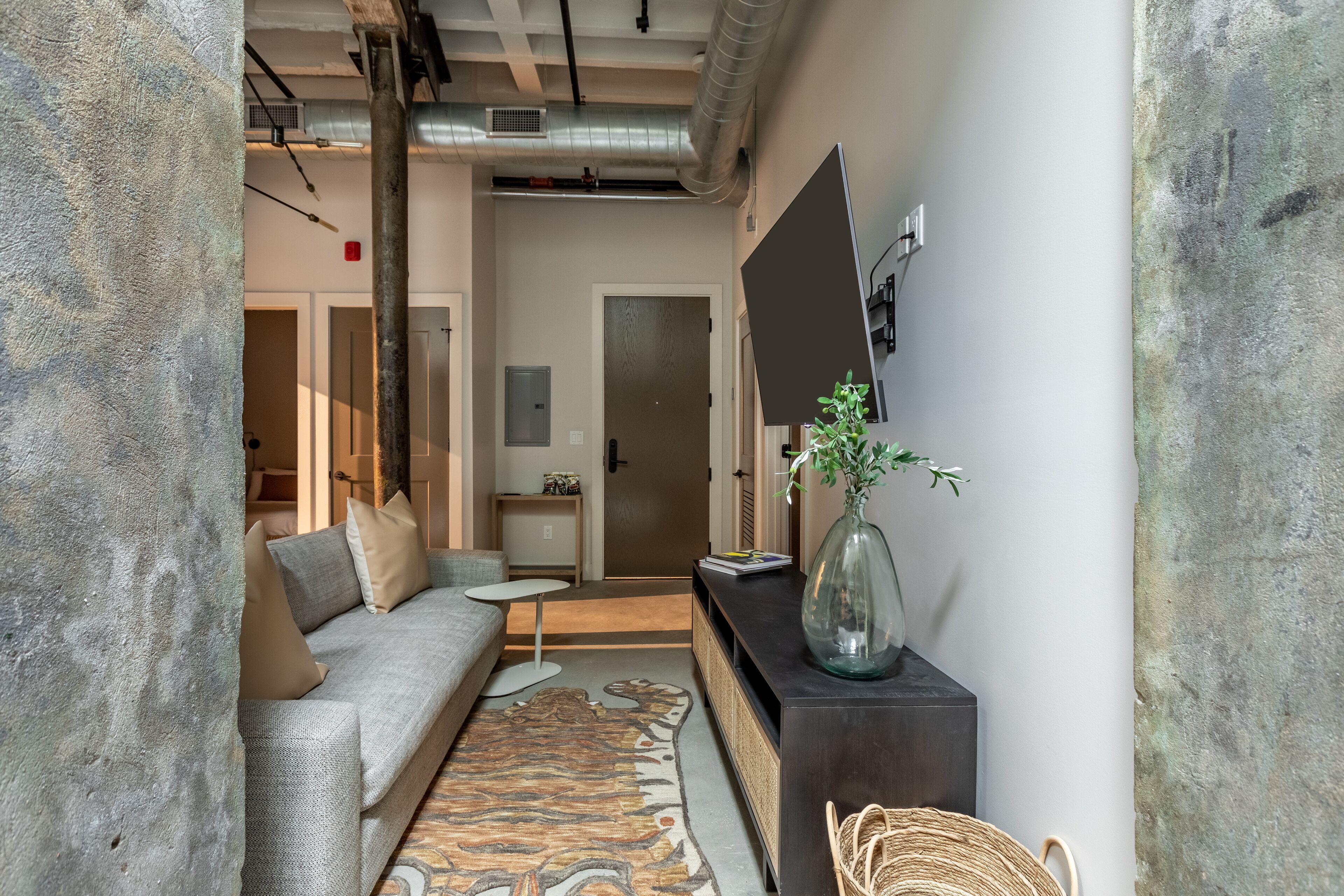 A modern living room with a grey sofa, a small coffee table, a decorative rug, and a dark console table with a vase.