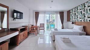 A hotel room with a TV, wooden furniture, a balcony with curtains, and a patterned wall. - Nanthana Villa (Pattaya)