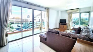 A spacious living room with a large window, a flat-screen TV, and a leather sofa. - Nanthana Villa (Pattaya)