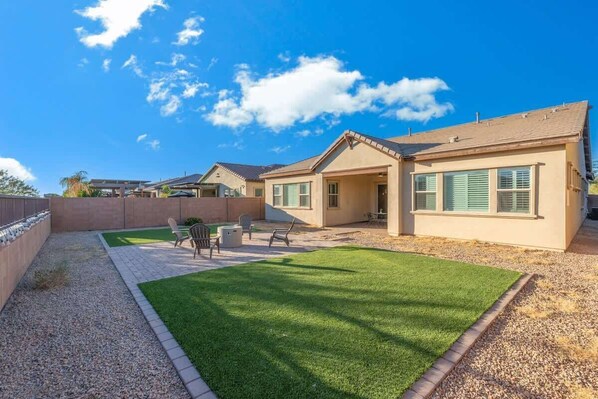 A residential property with a well-maintained lawn, patio furniture, and a clear blue sky.
