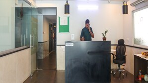 A reception desk with a sign, a ceiling fan, and a plant. - Destino by Halcyon Hitec City (Hyderabad)