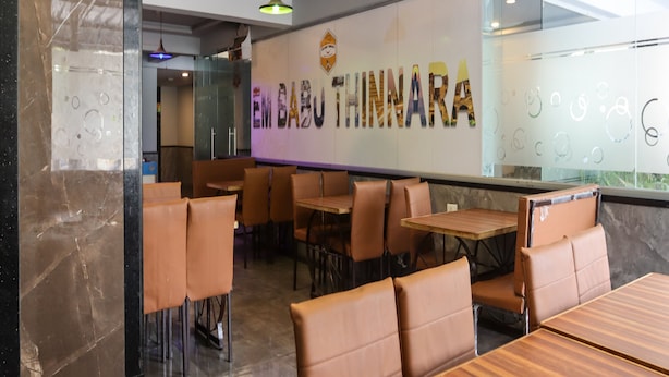 A restaurant interior with a modern design, featuring a marble wall, wooden tables, and cushioned chairs. - Destino by Halcyon Hitec City (Hyderabad)