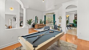 Una sala de estar moderna con mesa de billar, un sofá y un comedor con una mesa y sillas.