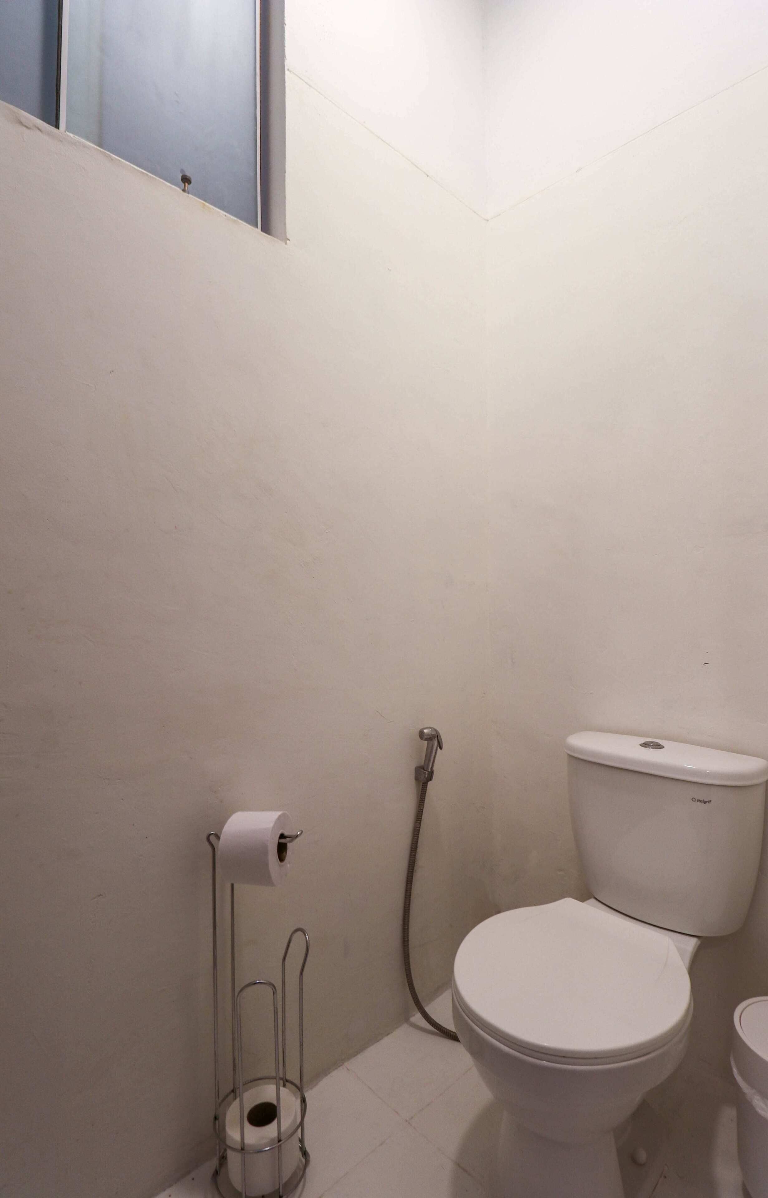 Un baño pequeño con inodoro, un dispensador de toallas de papel y un cabezal de ducha.
