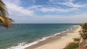 Una playa con cielos despejados, aguas tranquilas y barcos.