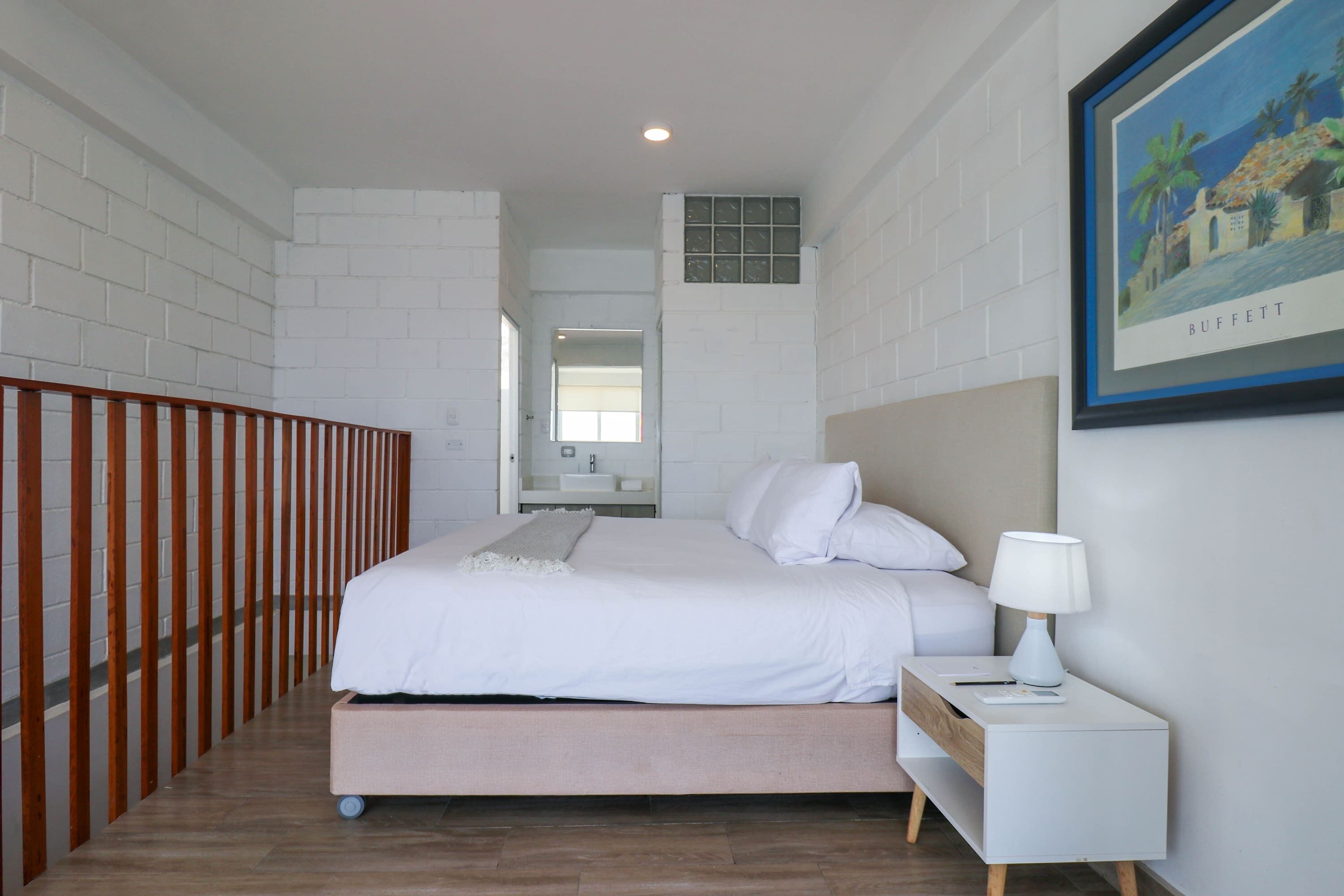 A bedroom with a bed, nightstand, and a framed picture on the wall.