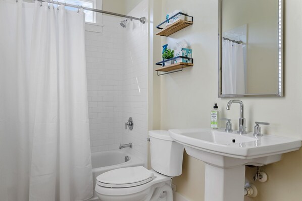 Un baño con ducha, inodoro, lavamanos y espejo.