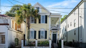 A two-story house with a front porch, a small balcony, and a gated entrance. - Edisto & Cooper House | Sleeps 14 | Full House (Charleston)