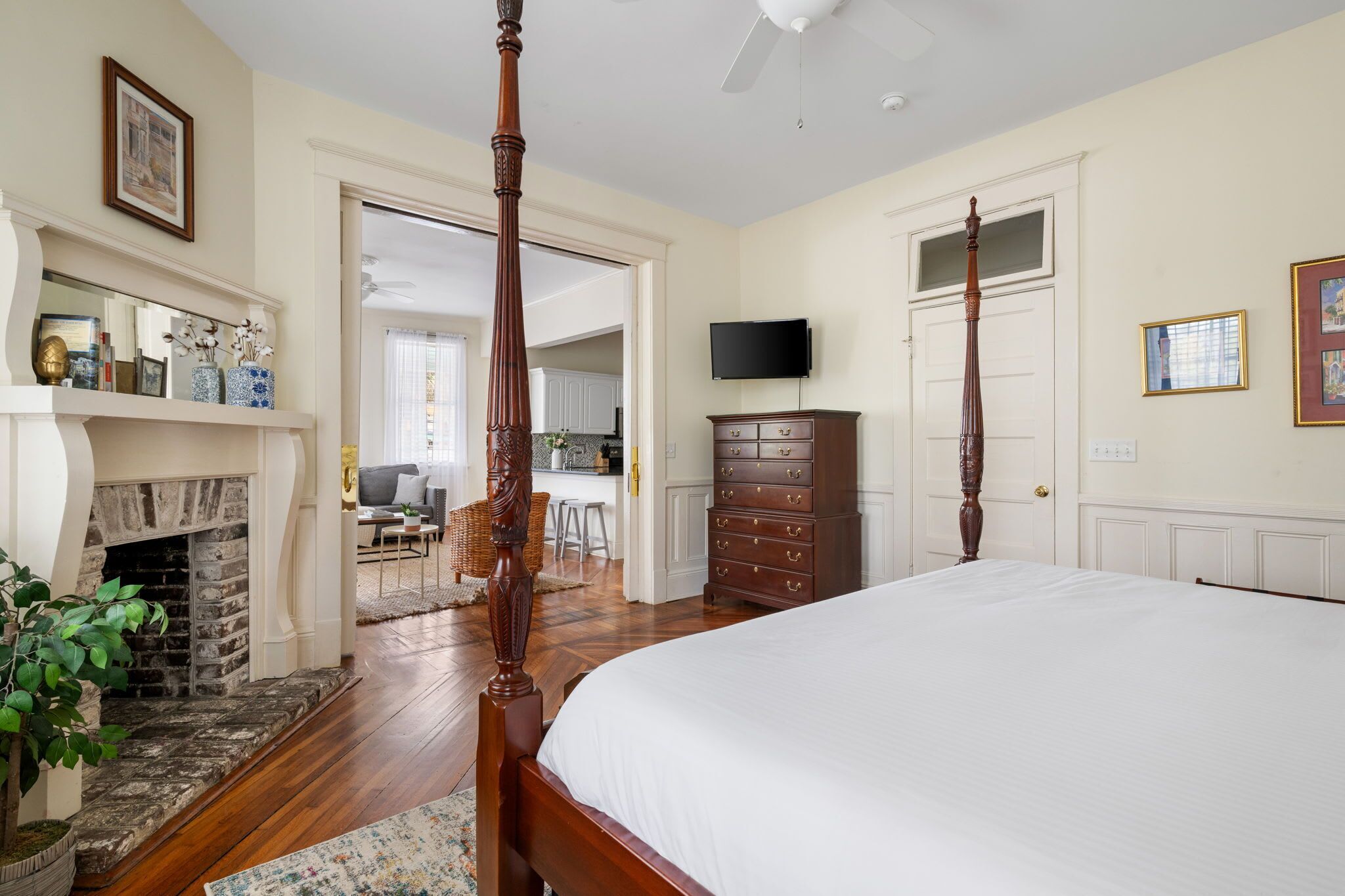 A bedroom with a four-poster bed, a fireplace, a television, and a dresser.