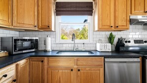 A kitchen with wooden cabinets, a microwave, a toaster, a sink, and a dishwasher. - Historic Condo Just Steps to Upper King Street (Charleston)