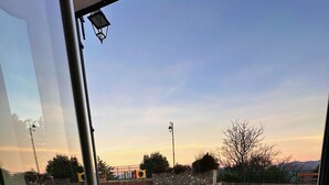 A view from inside a building looking out to a paved area with potted plants, a stone wall, and a playground in the distance. - Nirvana Experience bed and breakfast (Noepoli)