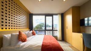 A modern hotel room with a large bed, a TV, and a balcony with a city view. - Mihman Tuzla (Tuzla)