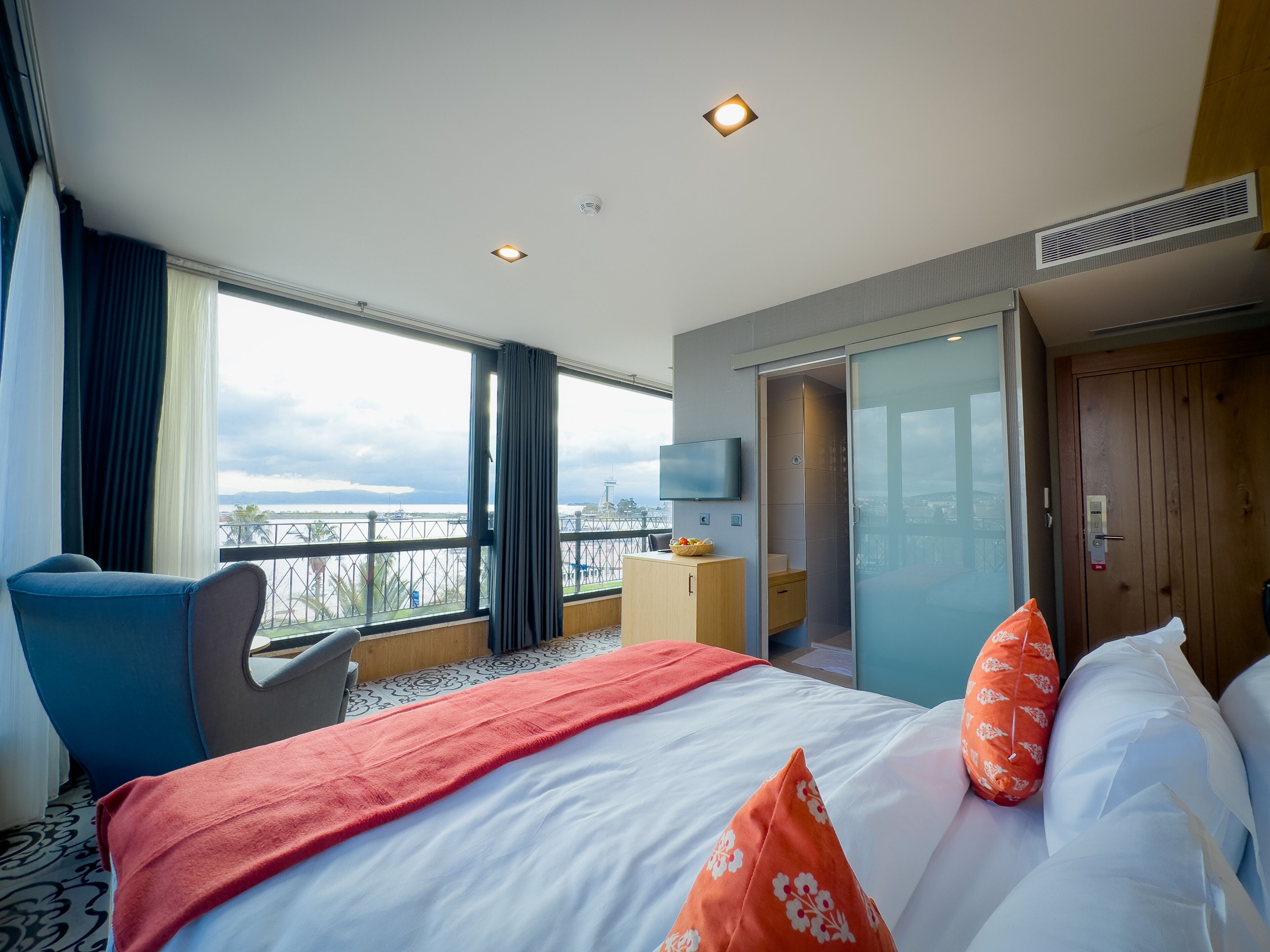 A hotel room with a large bed, a TV, a desk, and a view of the cityscape.