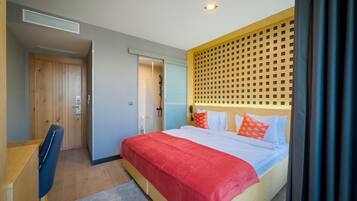 Habitación de hotel con cama, escritorio, ducha y pared divisoria de madera.