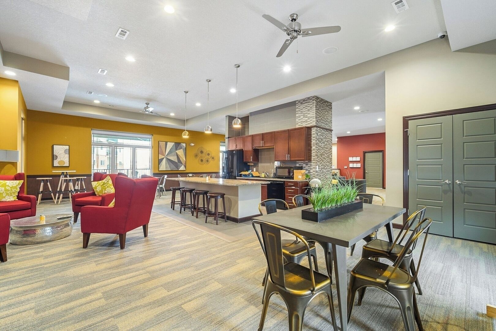Een moderne woonkamer met rode banken, een eethoek met een lange tafel, en een keuken met houten kasten.