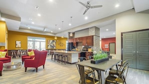 Ein modernes Wohnzimmer mit roten Sofas, ein Essbereich mit einem langen Tisch und eine Küche mit Holzausbau.
