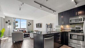 A modern kitchen with a dishwasher, stove, and microwave. - Near Stampede/ BMO Centre w Prkg & Gym (+18) (Calgary)