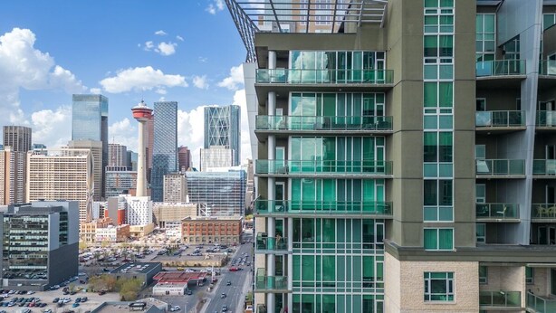 A modern multi-story building with large windows and a unique rooftop design. - Near Stampede/ BMO Centre w Prkg & Gym (+18) (Calgary)