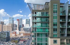 A modern multi-story building with large windows and a unique rooftop design. - Near Stampede/ BMO Centre w Prkg & Gym (+18) (Calgary)