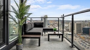 En balkon med sofa, sofabord og en potteplante.