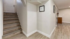 Ein Flur mit einer Holztreppe, weißen Wänden und Holzdielen.