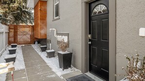 Ein Haus mit einer schwarzen Tür, einer kleinen Veranda und einem schneebedeckten Boden.
